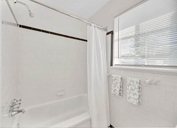 A white bathroom with a tub and a window.