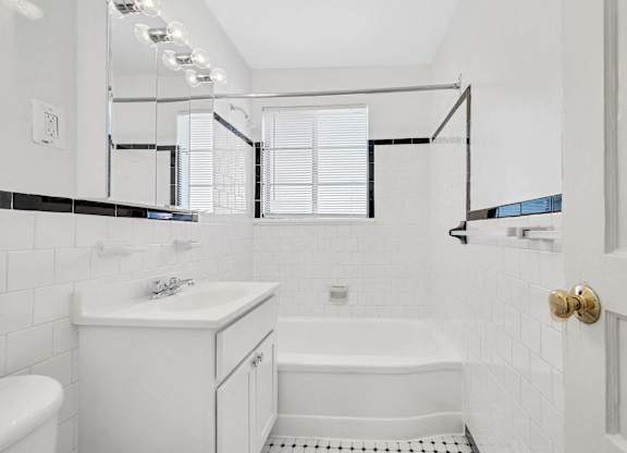 A white bathroom with a tub, sink, and toilet.