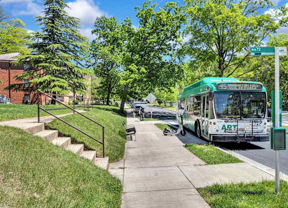 A green bus with the word ART on the front is driving down a street.