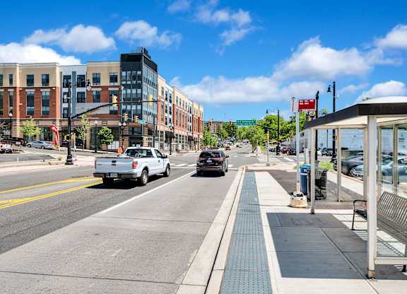 A city street with a bus stop and cars driving down the road.