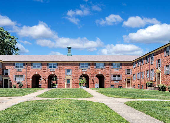 A red brick building with a green roof and a clear blue sky above.