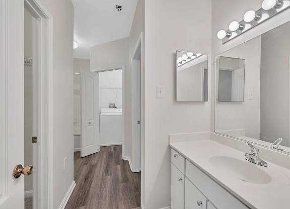 A bathroom with a sink, mirror, and lighting fixture.