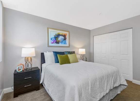 A bedroom with a bed, nightstands, and a painting on the wall.