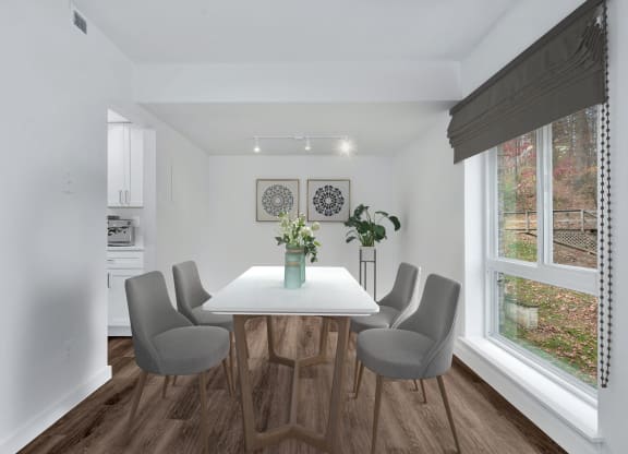 a dining room with a white table and chairs and a large window