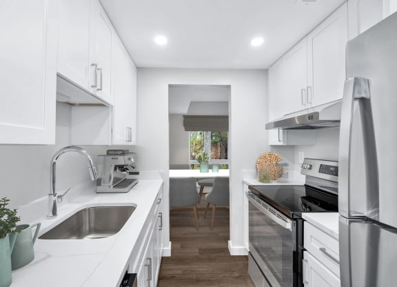 a white kitchen with stainless steel appliances and white cabinets