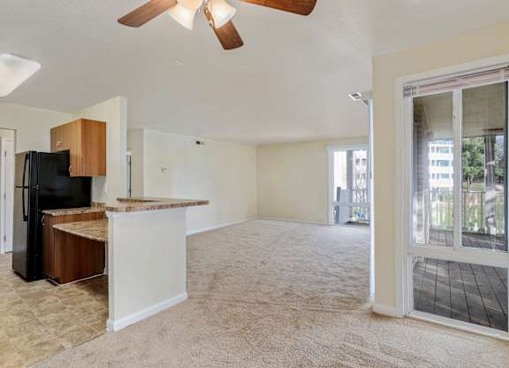 an empty living room and kitchen with a door to a balcony