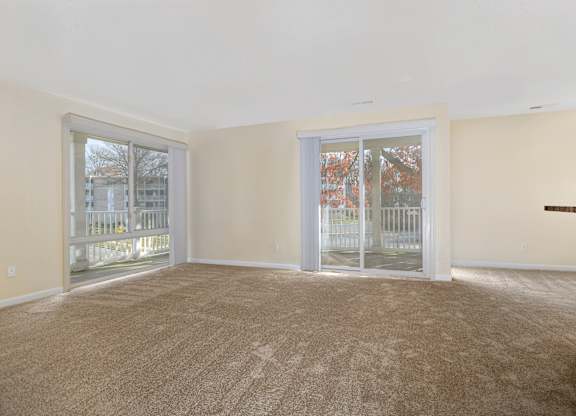 an empty living room with sliding glass doors to a balcony