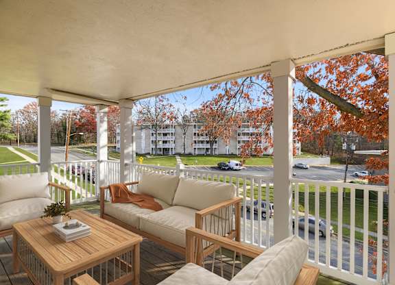 A white porch with a table and chairs.