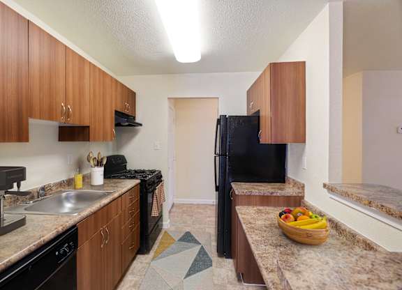 A kitchen with brown cabinets and black appliances.