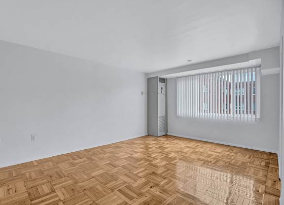 A room with a wooden floor and a door leading to another room.