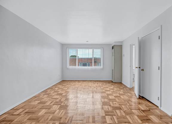 A room with wooden flooring and white walls.