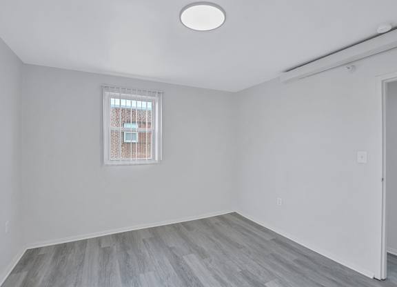 A room with a window and a wooden floor.