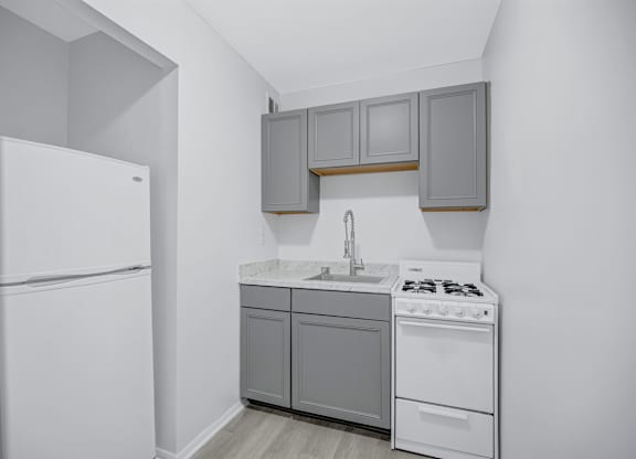 A small kitchen with white appliances and grey cabinets.