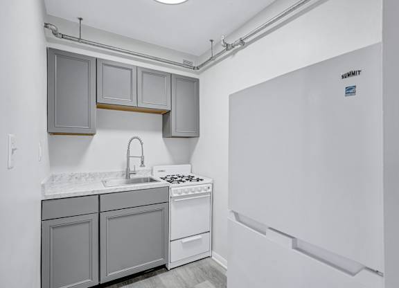 A kitchen with a white fridge and a white counter top.