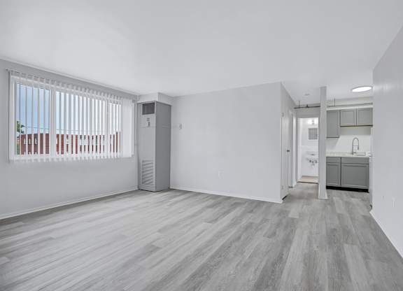 A spacious room with a wooden floor and white walls.