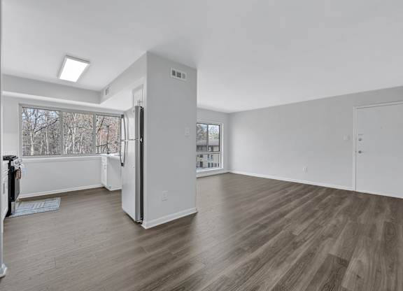A spacious room with wooden floors and white walls.