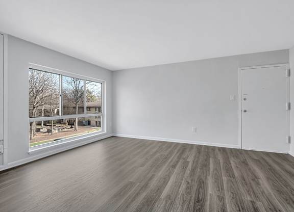 A room with a large window and a wooden floor.