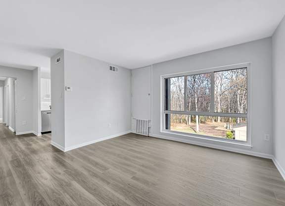 A room with a large window and a view of trees outside.