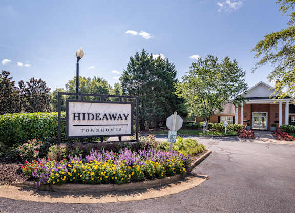 A sign for Hideaway Townhomes is in front of a house.