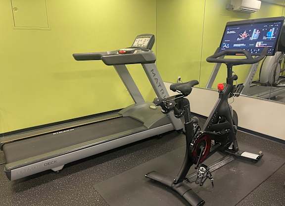 A treadmill and a stationary bike are in a gym.