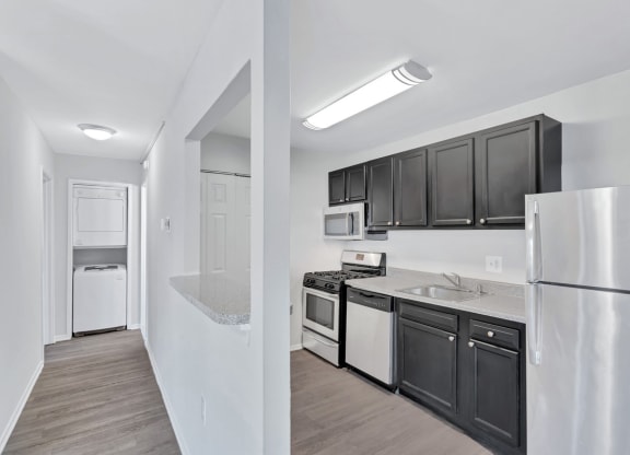 a kitchen with black cabinets and white appliances and a refrigerator