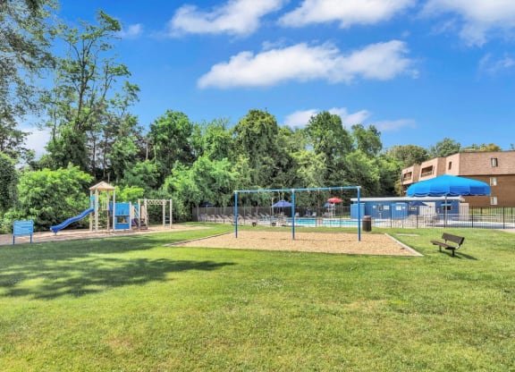 a grassy area with a playground and a building in the background