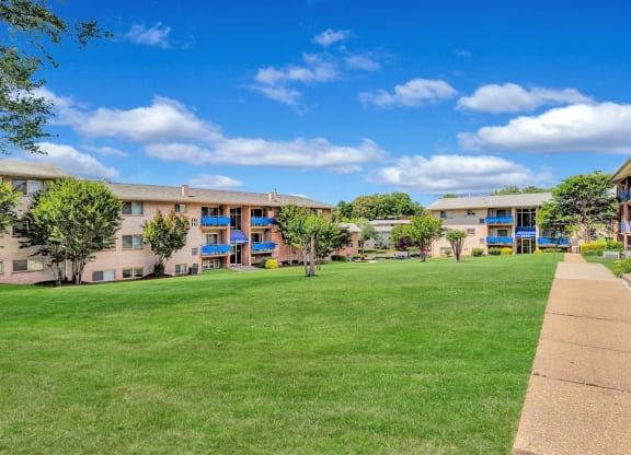 a grassy area with trees and buildings in the background