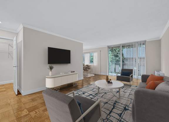 A living room with a grey couch, a white coffee table, and a flat screen TV mounted on the wall.