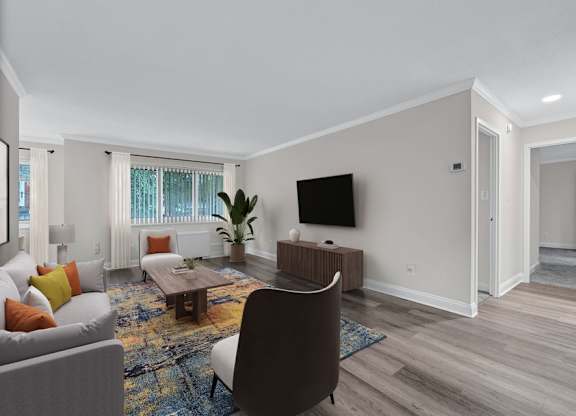 A living room with a grey couch, a brown chair, a wooden coffee table, a flat screen TV, and a rug.