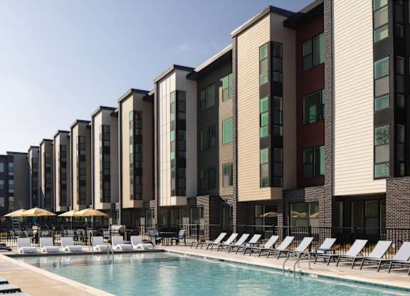 A row of modern apartment buildings with a pool in front.
