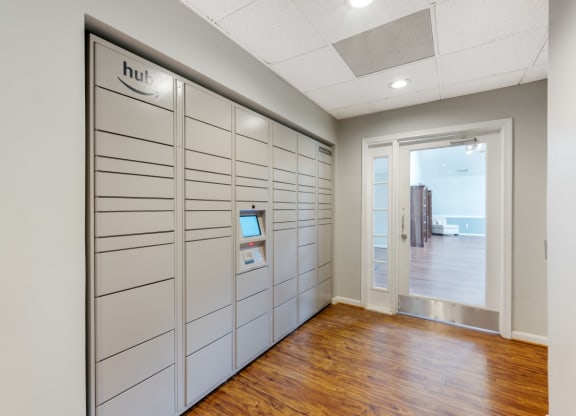 a long hallway with white cabinets and a door to a room with a wood floor
