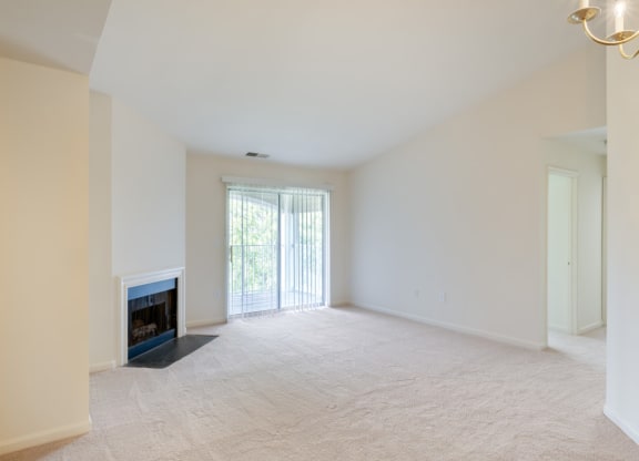 an empty living room with a fireplace and a sliding glass door