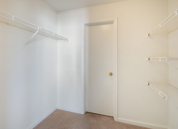 a walk in closet with white walls and a white door