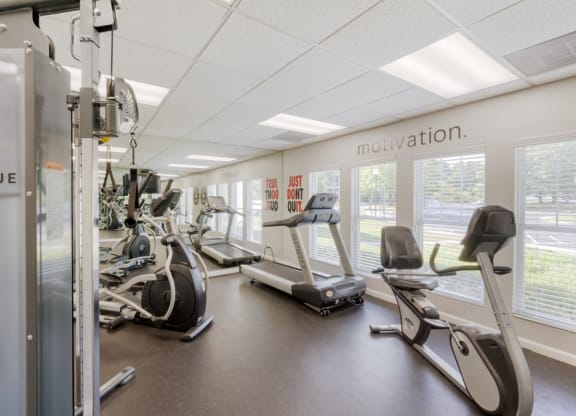 a gym with cardio equipment and windows in a building