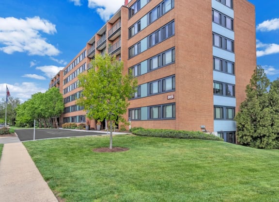 a large brick building with green grass and a tree in front of it