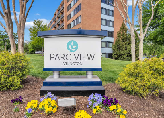 an apartment building with a park view sign in front of flowers