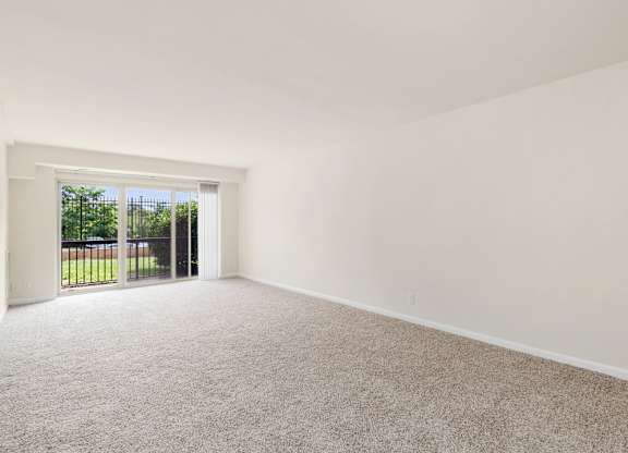A room with a carpeted floor and a sliding glass door leading to a backyard.