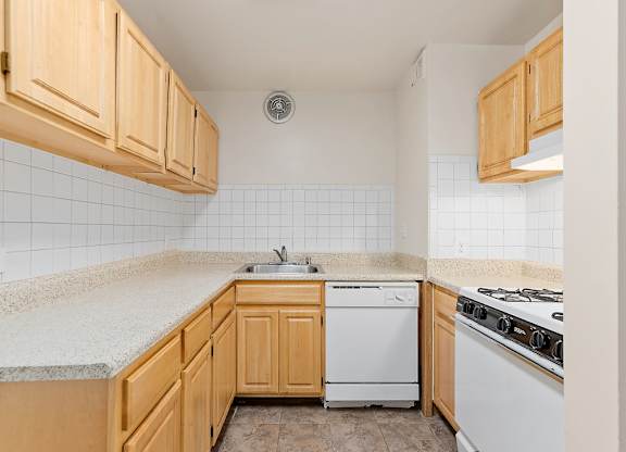 A kitchen with wooden cabinets and a white dishwasher.