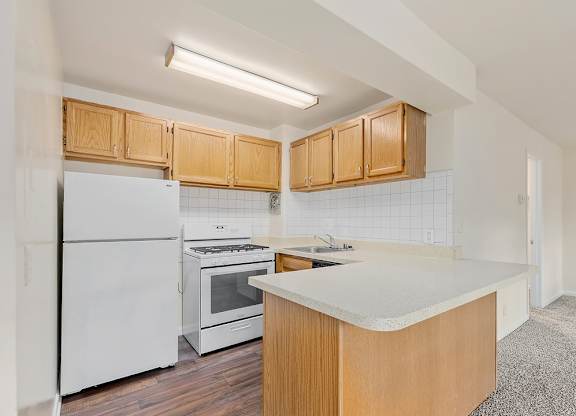 A kitchen with white appliances and wooden cabinets.