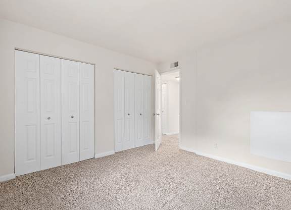 A white room with a carpeted floor and three white doors.