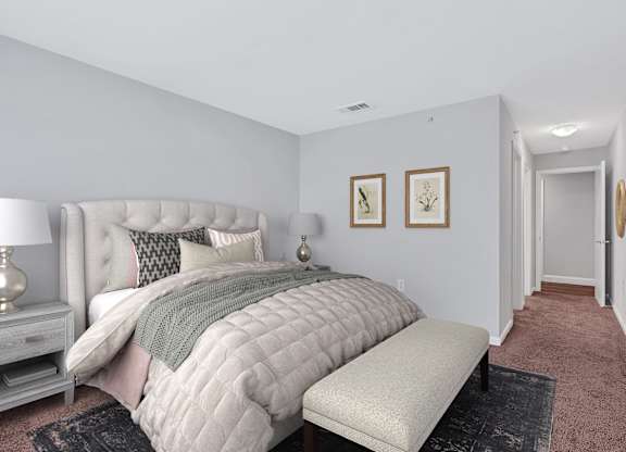 A spacious apartment bedroom with large bed and bench at the foot and hallway to closet and bathroom.
