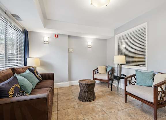 A living room with a brown couch, two chairs, and a table with lamps.
