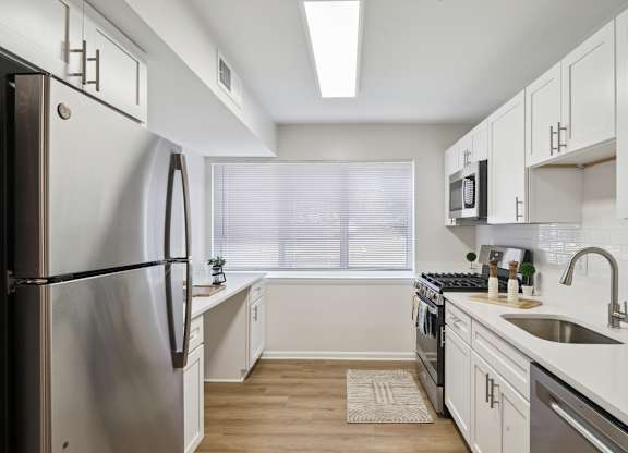 A modern kitchen with a stainless steel refrigerator and white cabinets.