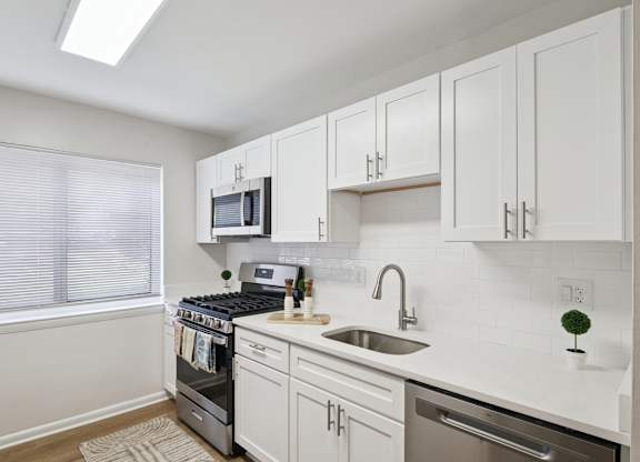 A kitchen with white cabinets and a stove top oven.