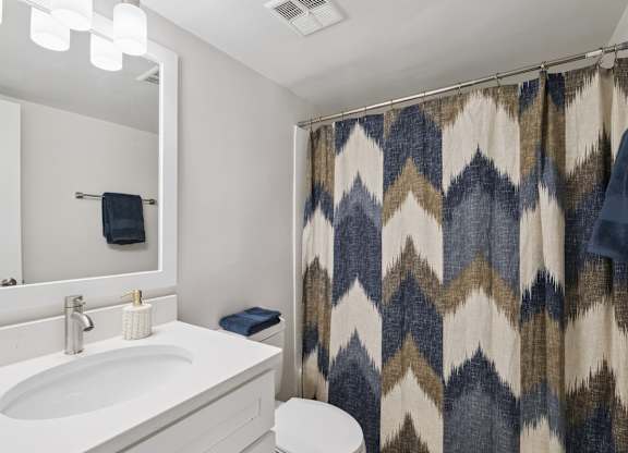 A bathroom with a white sink and a shower curtain with a chevron pattern.