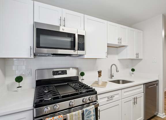 A modern kitchen with white cabinets and a stainless steel stove.