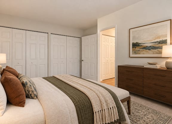 A bedroom with a bed, pillows, a blanket, a dresser, and a painting on the wall.