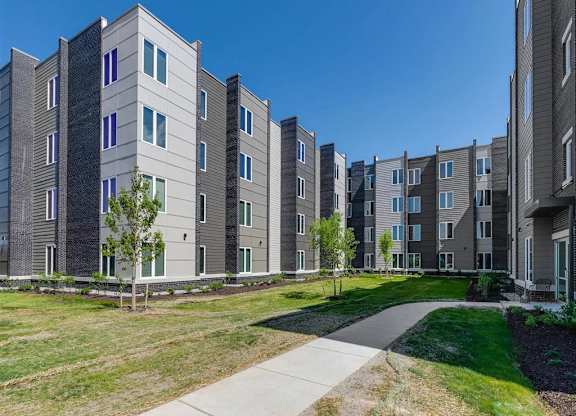 an exterior view of an apartment building with grass and trees