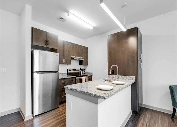 A kitchen with a refrigerator, sink, and cabinets.