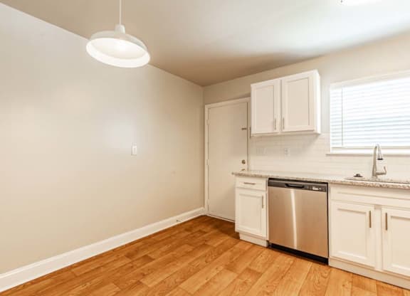 an empty kitchen with white cabinets and a sink and a dishwasher